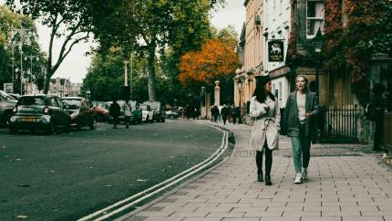 two women walking along a street, talking climate